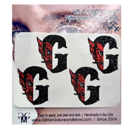 Four black glitter letter G decals with red glitter devil face details, presented on a white backing card labeled 'GLITTER ART'.
